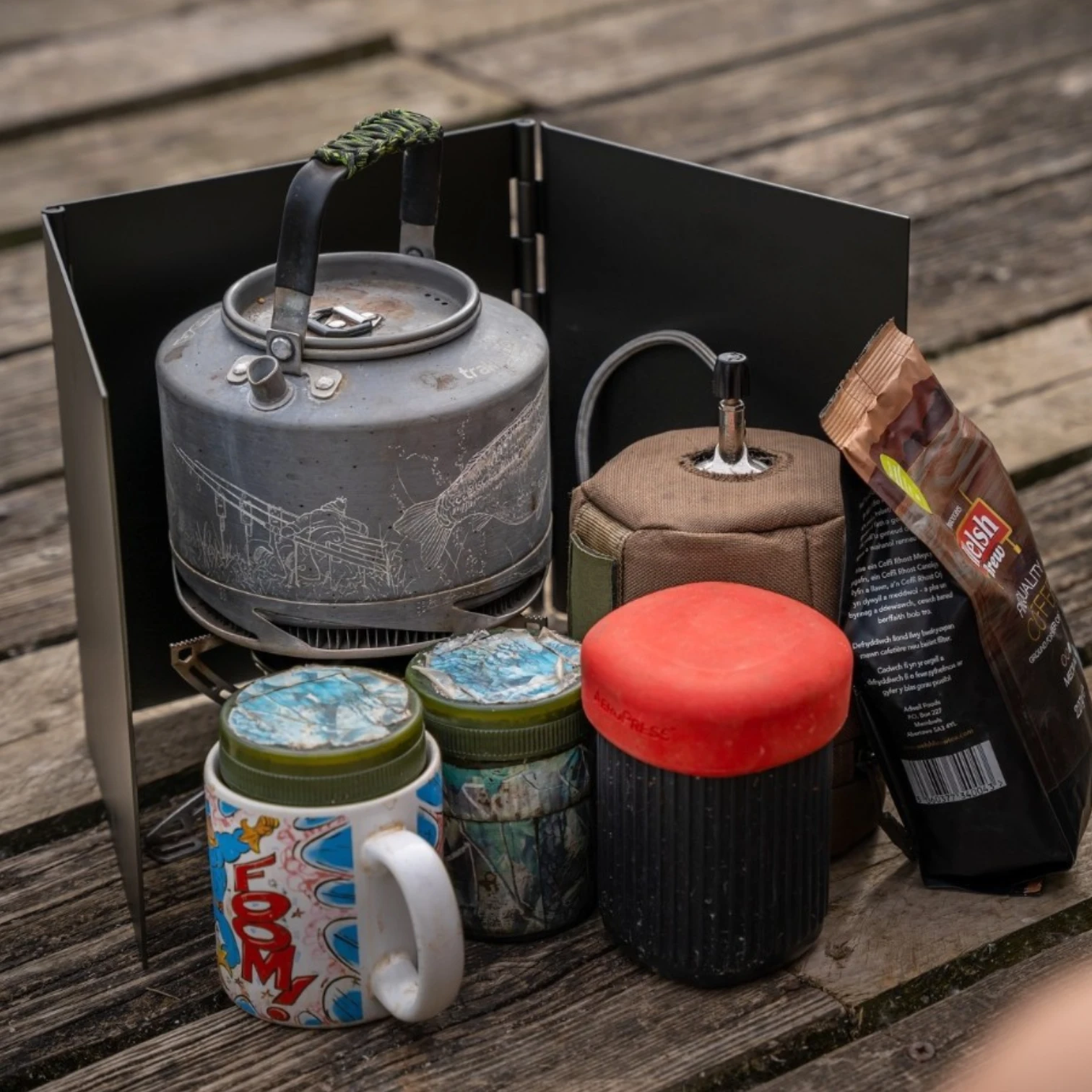 Korda Windshield Large in use outdoors shielding a fishing stove and cooking setup from wind