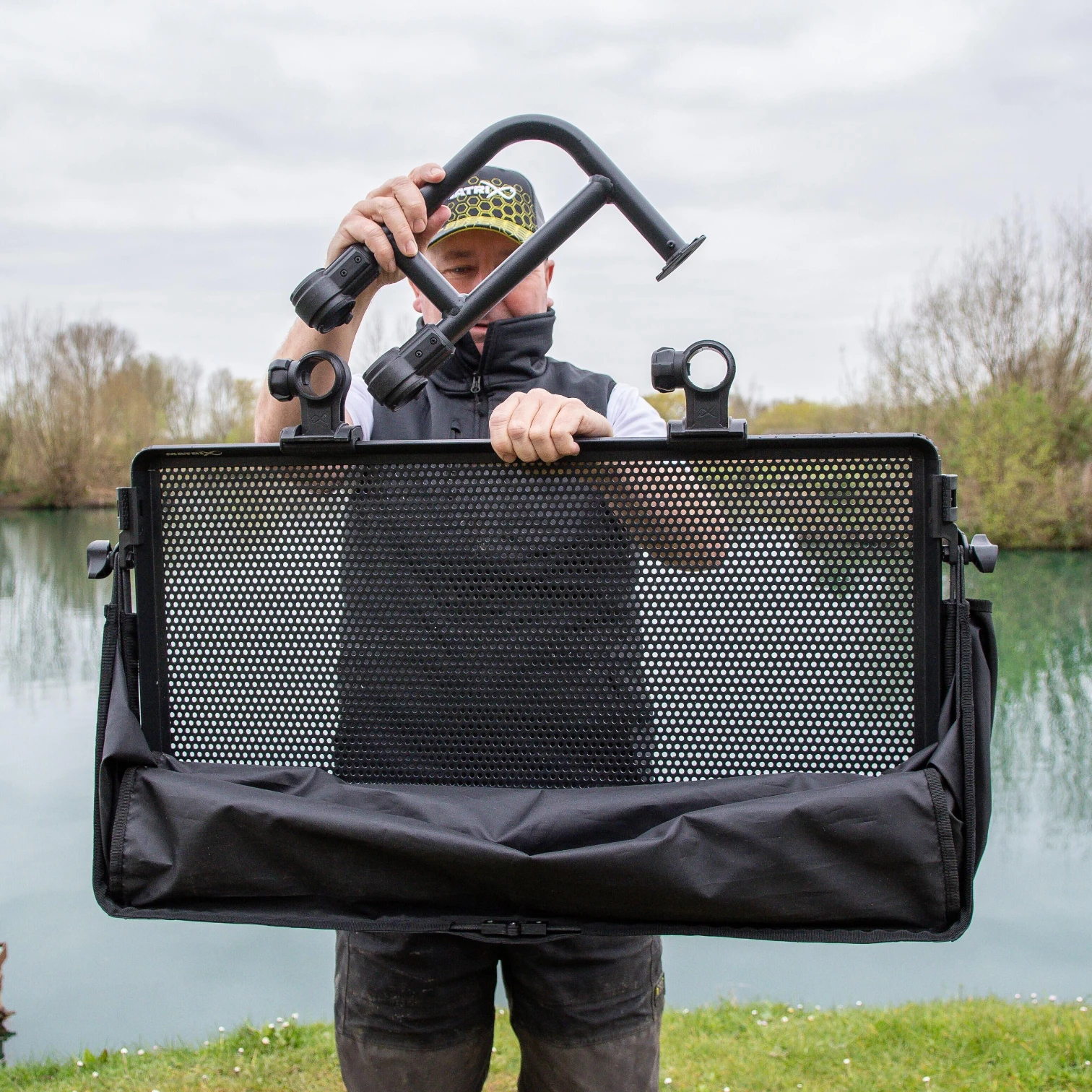 Angler holding the Matrix Sliding Side Tray and Cover showing the full tray, support arm, and protective cover