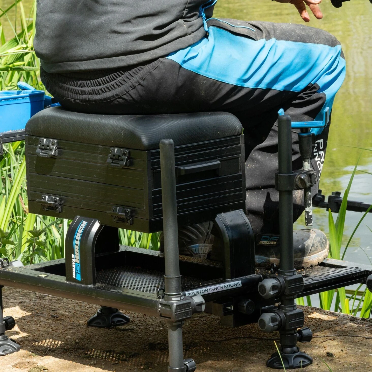 Angler seated on the Preston Ignition Station SL Seatbox while fishing on a match fishing peg